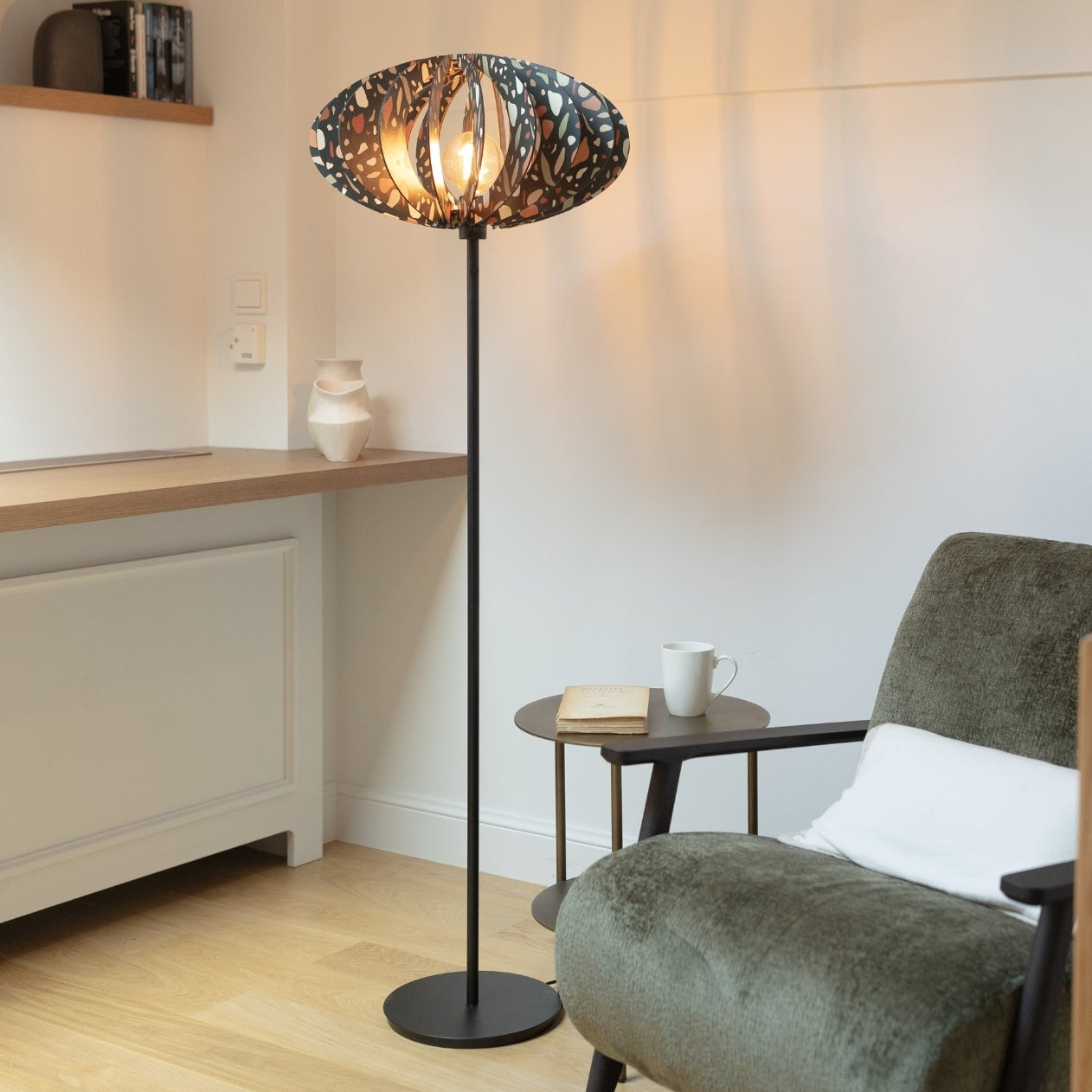 An elegant 'Adele' floor lamp with a geometric patterned shade in a living room setting, providing ambient lighting.